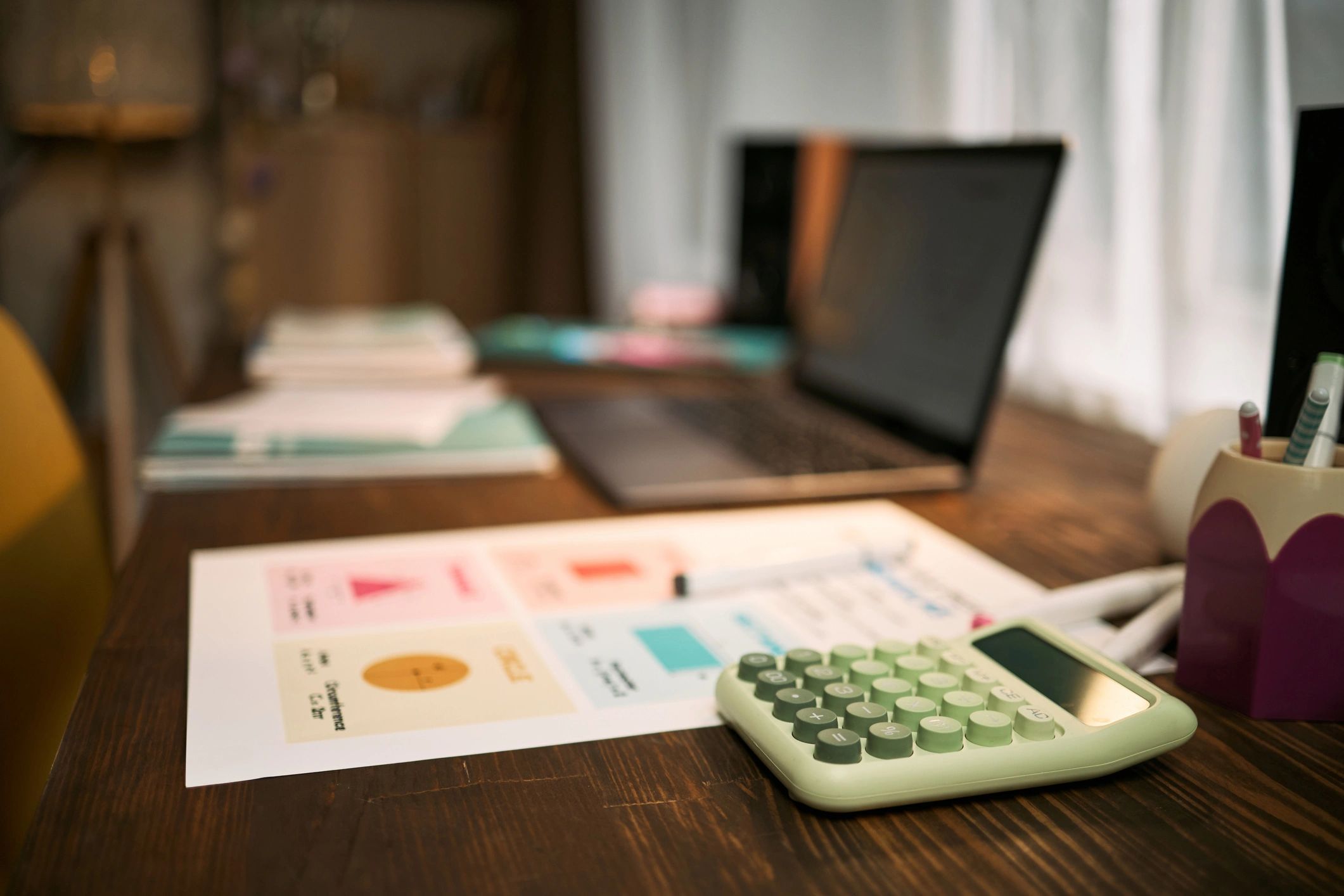 Desk with laptop, calculator, and charts representing business data and documentation